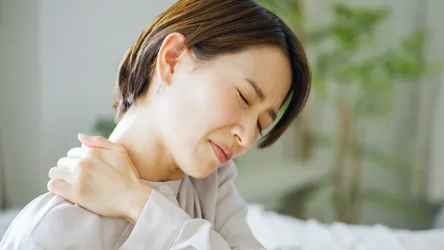 肩をおさえてつらそうな女性